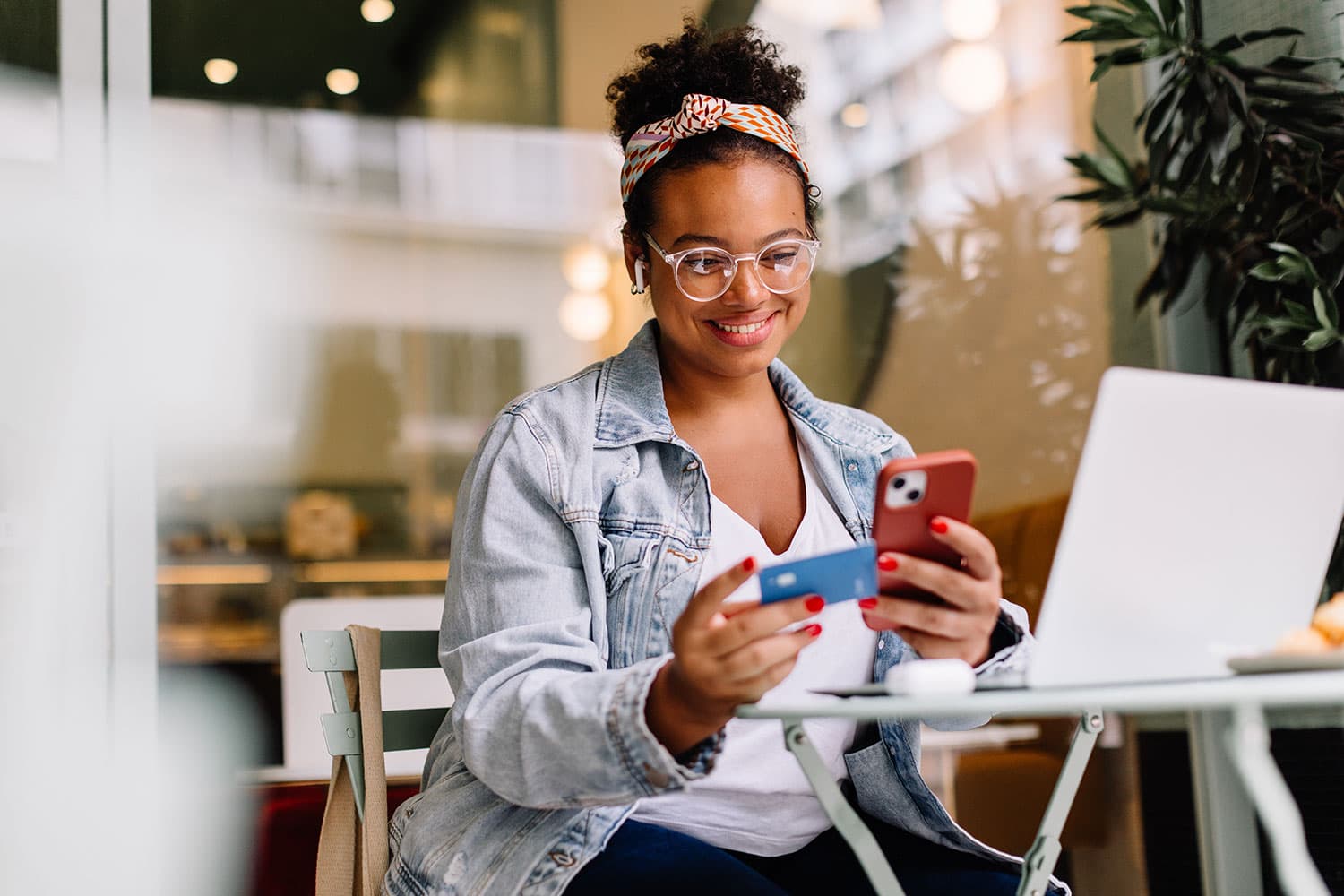 Woman using credit card with mobile device and laptop
