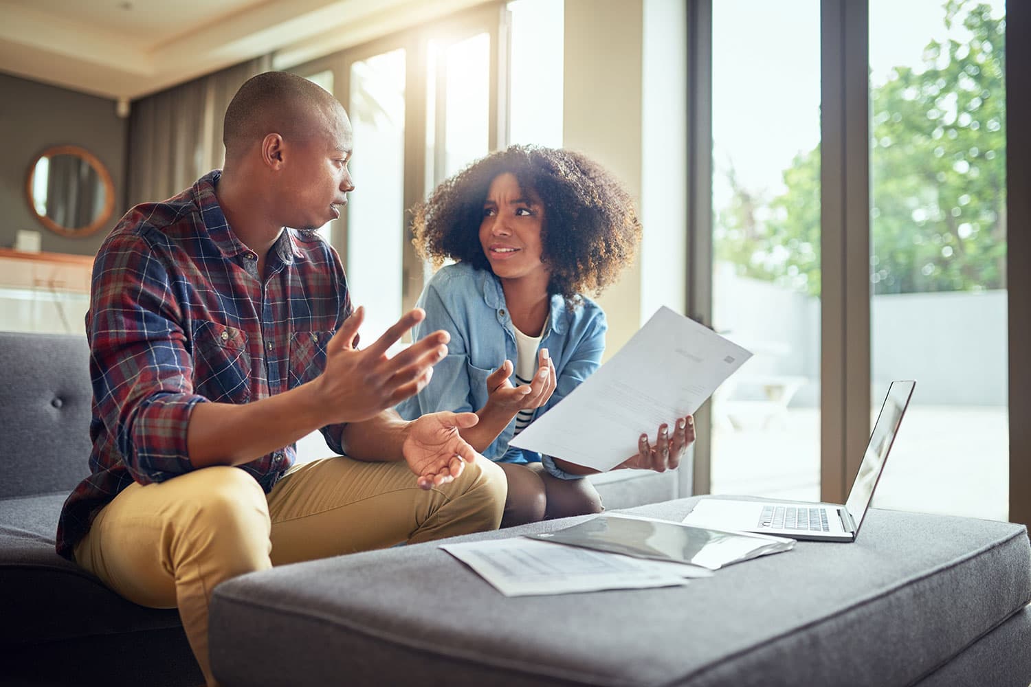 couple with paperwork and laptop looking confused