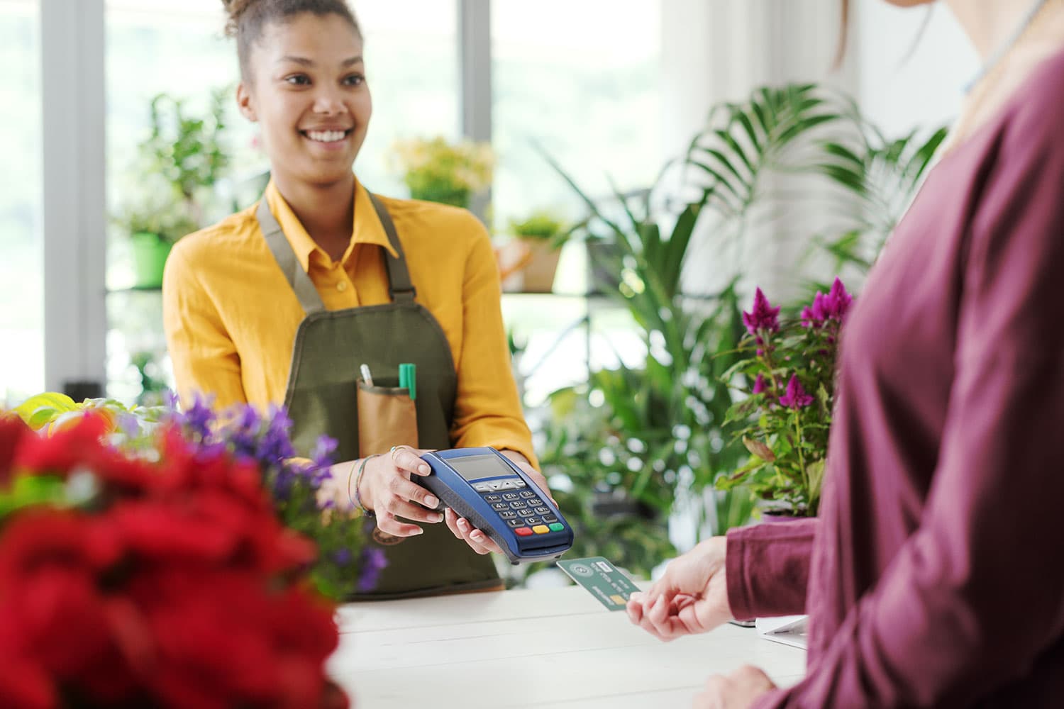 woman paying at flower shop with credit card processing machine